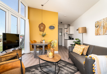 Moderne leefruimte in tiny house Knilles op Tusken de Marren in Nederland, met gezellige gele accenten.