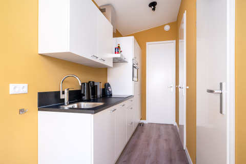 Cocina pequeña y moderna en la tiny house Knilles en Tusken de Marren, Países Bajos, paredes amarillas