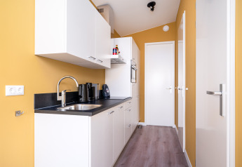 Cuisine compacte et moderne dans la tiny house Knilles à Tusken de Marren, Pays-Bas, murs jaunes