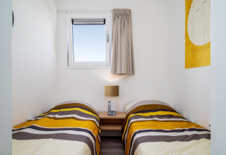 Pequeño dormitorio en Knilles, Tusken de Marren, Países Bajos, con dos camas individuales y decoración moderna.