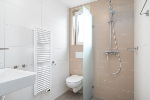 Baño moderno y compacto en Knilles, Tusken de Marren, Países Bajos, con ducha y retrete suspendido.