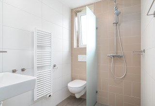 Baño moderno y compacto en Knilles, Tusken de Marren, Países Bajos, con ducha y retrete suspendido.