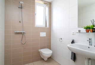Modernes kleines Badezimmer mit Wandtoilette, Waschbecken und Dusche im Knilles, Tusken de Marren, Niederlande.