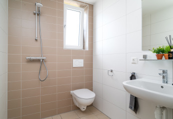 Modern kleine badkamer met hangtoilet, wastafel en douche in Knilles, Tusken de Marren, Nederland.