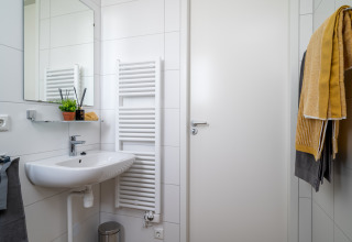 Modernes Badezimmer im Tiny House Knilles bei Tusken de Marren, Niederlande, mit Waschbecken und Handtüchern.