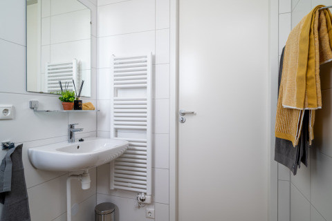Modern bathroom in tiny house Knilles at Tusken de Marren, Netherlands, with sink and yellow towels.