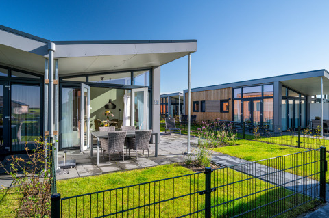 Modern tiny house Knilles at Tusken de Marren, Netherlands, with sunny terrace, garden, and outdoor seating.