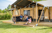 Familia relajándose frente a la tienda safari Stuuflodge en Kampeerdorp de Zandstuve, Países Bajos.