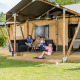 Familia relajándose frente a la tienda safari Stuuflodge en Kampeerdorp de Zandstuve, Países Bajos.
