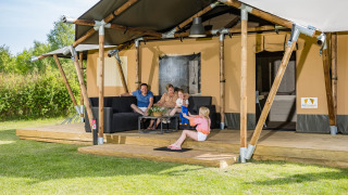 Familie genießt Zeit vor einem Safari-Zelt Stuuflodge im Kampeerdorp de Zandstuve, Niederlande.