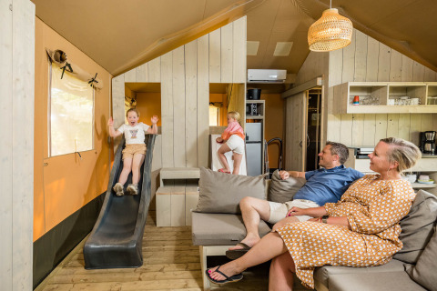 Famiglia si diverte nella tenda safari Stuuflodge con scivolo a Kampeerdorp de Zandstuve, Paesi Bassi.