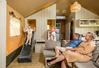 Familie nyder tid sammen i en Stuuflodge safari-telt med rutsjebane ved Kampeerdorp de Zandstuve, Holland.