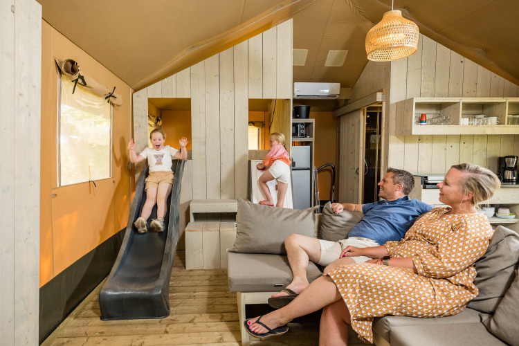 Familia disfruta en una tienda safari Stuuflodge con tobogán interior en Kampeerdorp de Zandstuve, Países Bajos.