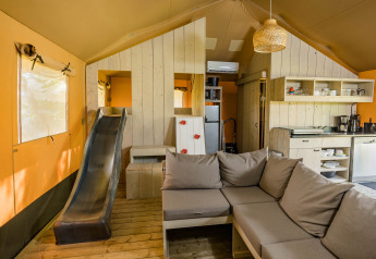 Indvendig udsigt af en Stuuflodge safaritelte med sofa, rutsjebane og køkken i Kampeerdorp de Zandstuve.