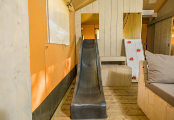 Vue intérieure de la tente safari Stuuflodge avec toboggan et mur d'escalade au Kampeerdorp de Zandstuve, Pays-Bas.
