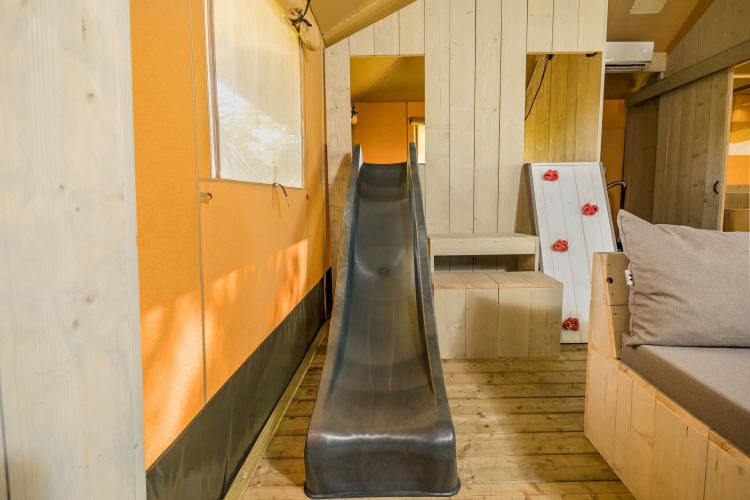Binnenaanzicht van de Stuuflodge safaritent met glijbaan en klimwand in Kampeerdorp de Zandstuve, Nederland.