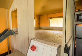 Vista interior de la tienda safari Stuuflodge con zona de juegos, tobogán y cocina en Zandstuve, Holanda.