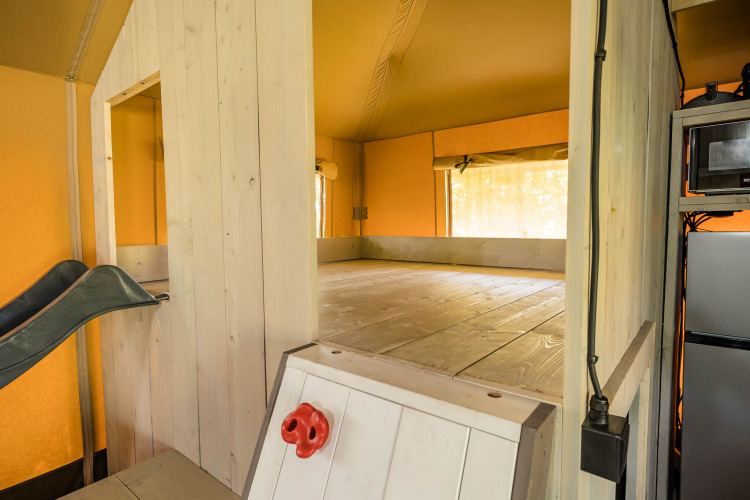Binnenzicht van de Stuuflodge safaritent met speelruimte, glijbaan en keuken in Zandstuve, Nederland.
