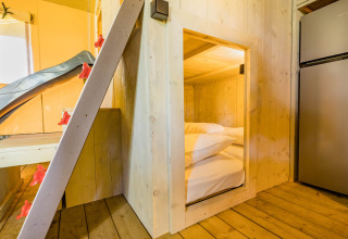 Vista interna della tenda safari Stuuflodge a Kampeerdorp de Zandstuve con pareti in legno e letto.