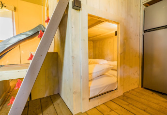 Vista interior de una tienda safari Stuuflodge en Kampeerdorp de Zandstuve con paredes y cama de madera.