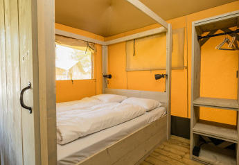 Schlafzimmer im Stuuflodge-Safarizelt im Kampeerdorp de Zandstuve, Niederlande, mit gemütlichem Bett.
