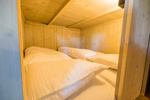 Innenaufnahme einer gemütlichen Schlafkabine mit zwei Einzelbetten aus Holz im Stuuflodge, Kampeerdorp de Zandstuve.
