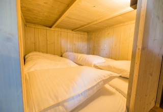 Binnenaanzicht van een knusse houten slaapcabine met twee eenpersoonsbedden in Stuuflodge, Kampeerdorp de Zandstuve.