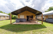 Tienda safari Stuuflodge Bella con terraza de madera y mobiliario exterior en Kampeerdorp de Zandstuve, Países Bajos.