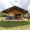 Stuuflodge Bella safaritent met houten veranda, loungeset en picknicktafel bij Kampeerdorp de Zandstuve, Nederland.