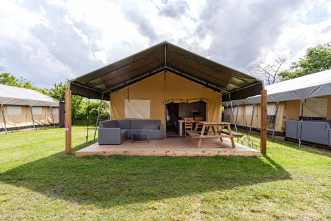 Tienda safari Stuuflodge Bella con terraza de madera y mobiliario exterior en Kampeerdorp de Zandstuve, Países Bajos.