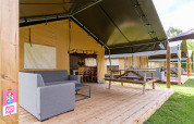 Safari-Zelt Stuuflodge Bella mit Holzterrasse, Loungesofa und Picknicktisch bei Kampeerdorp de Zandstuve.