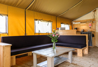 Interior de la tienda safari Stuuflodge Bella, con muebles de madera y un florero sobre la mesa.