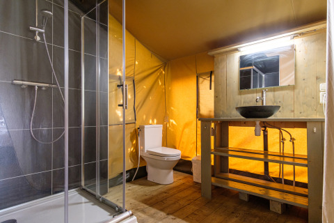 Baño en tienda safari Stuuflodge Bella en Kampeerdorp de Zandstuve, con ducha, inodoro y lavabo modernos.