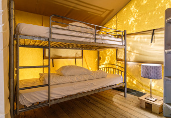 Innenansicht eines Safarizelts im Kampeerdorp de Zandstuve mit Etagenbett und Nachttischlampe.