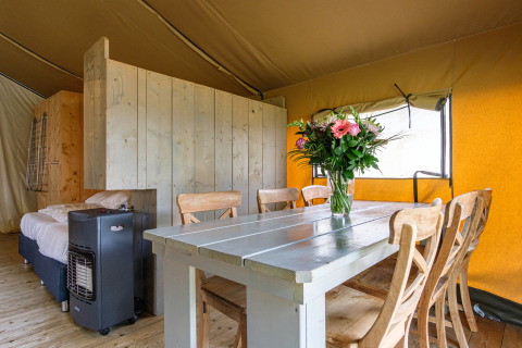 Innenraum des Stuuflodge Bella Safarizelts im Kampeerdorp de Zandstuve, Niederlande, mit Esstisch.