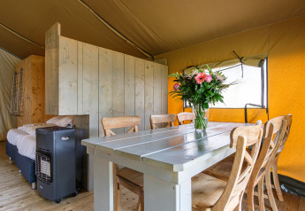 Innenraum des Stuuflodge Bella Safarizelts im Kampeerdorp de Zandstuve, Niederlande, mit Esstisch.
