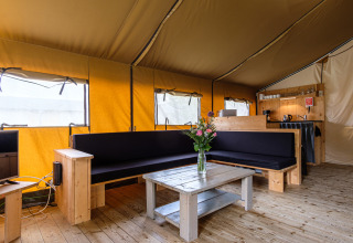 Vista interior de Stuuflodge Bella, una tienda safari con muebles de madera y sala cómoda en Holanda.