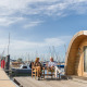 Par på terrassen foran et tiny house 'Water bubbles' ved Marina Parcs Almere, Nederlandene, omgivet af både.