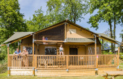 Familie nyder en solrig dag på terrassen af en Stuuflodge DeLuxe safari-telt i Kampeerdorp de Zandstuve.