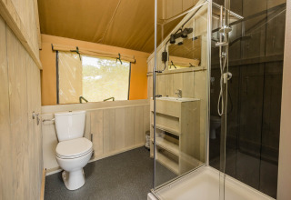 Baño con inodoro, ducha y lavabo en Stuuflodge DeLuxe, tienda safari en Kampeerdorp de Zandstuve, Países Bajos.