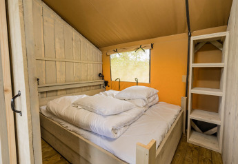 Camera da letto della Stuuflodge DeLuxe, tenda safari con letto e scaffale in legno nei Paesi Bassi.