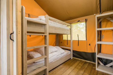 Interieur van een safaritent met stapelbedden en houten vloer bij Kampeerdorp de Zandstuve, Nederland.