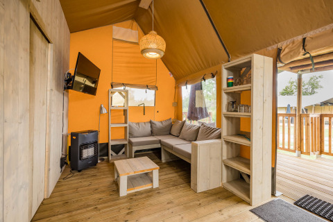 Indvendig udsigt af Stuuflodge DeLuxe safaritelten med sofa, hylder og vindue i Kampeerdorp de Zandstuve.