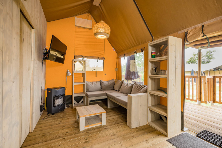 Innenansicht des Stuuflodge DeLuxe Safari-Zeltes mit Sofa, Regal und Fenster in Kampeerdorp de Zandstuve.