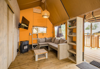 Vista interior de la tienda safari Stuuflodge DeLuxe con sofá y estantería en Kampeerdorp de Zandstuve.