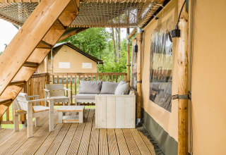 Outdoor wooden terrace with seating at Stuuflodge DeLuxe, a safari tent at Kampeerdorp de Zandstuve, Netherlands.