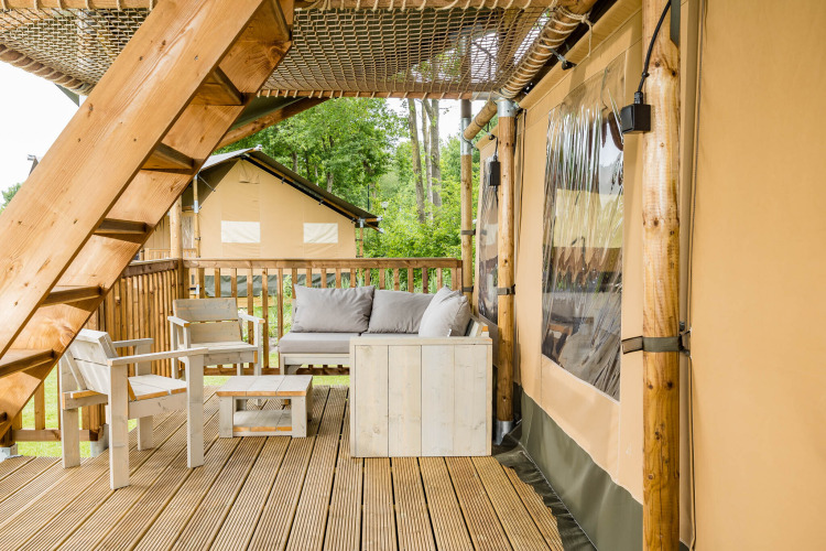 Terrasse mit Holzmöbeln an der Stuuflodge DeLuxe, einem Safarizelt im Kampeerdorp de Zandstuve, Niederlande.