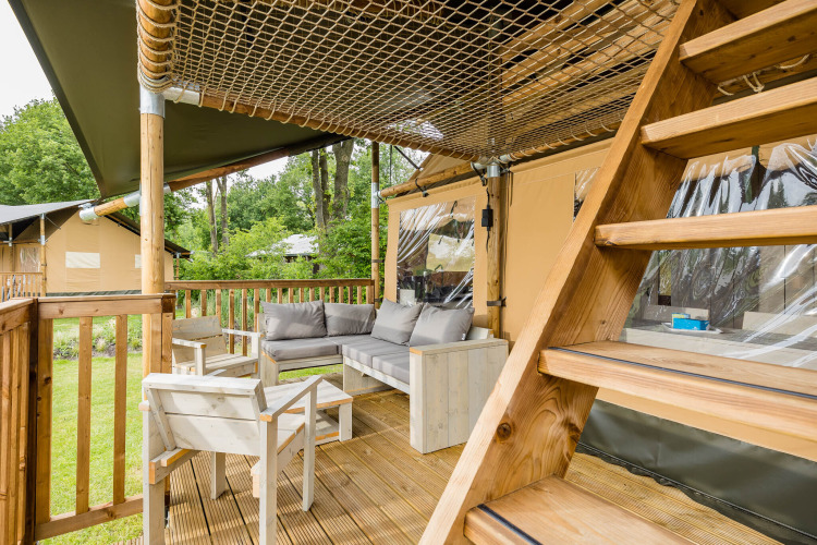 Gemütliche Terrasse mit Sofa und Stühlen im Stuuflodge DeLuxe-Safarizelt bei Kampeerdorp de Zandstuve.