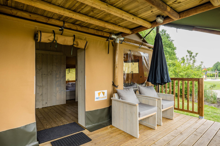 Terrasse des Stuuflodge DeLuxe Safarizelts mit Holzmöbeln im Kampeerdorp de Zandstuve, Niederlande.