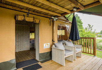 Porche de la tienda safari Stuuflodge DeLuxe con asientos de madera en Kampeerdorp de Zandstuve, Países Bajos.